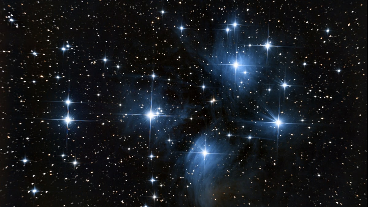Astrophotography capturing the Pleiades star cluster with vibrant stars in deep space.